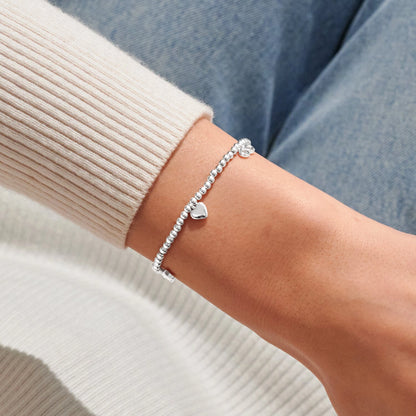 Model wearing silver stretch beaded bracelet with heart charm