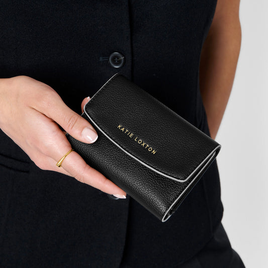 Model holding a fold over black vegan leather purse with contrasting sand coloured wax trim