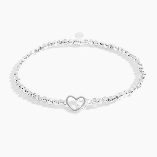 A silver beaded bracelet with two silver interlinking hearts