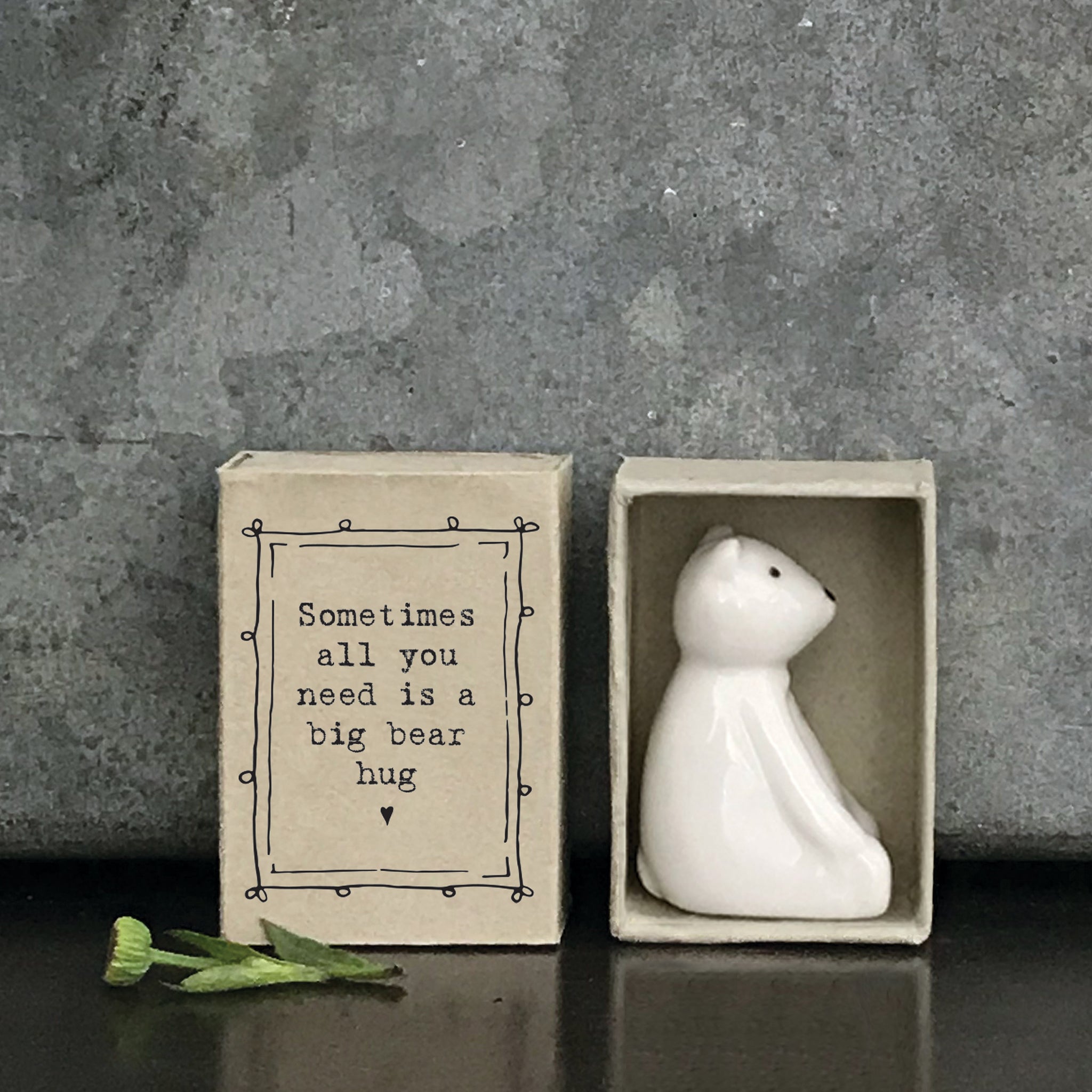 Minimalist white ceramic bear figurine in a box with a quote