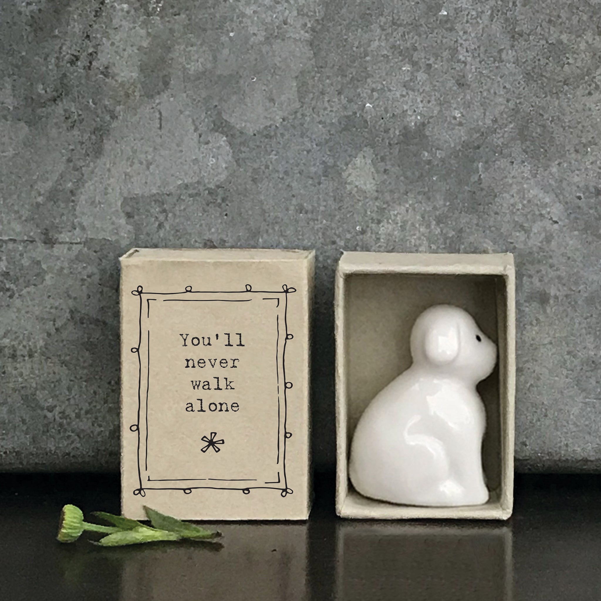 Minimalist white ceramic dog figurine in a box with a quote