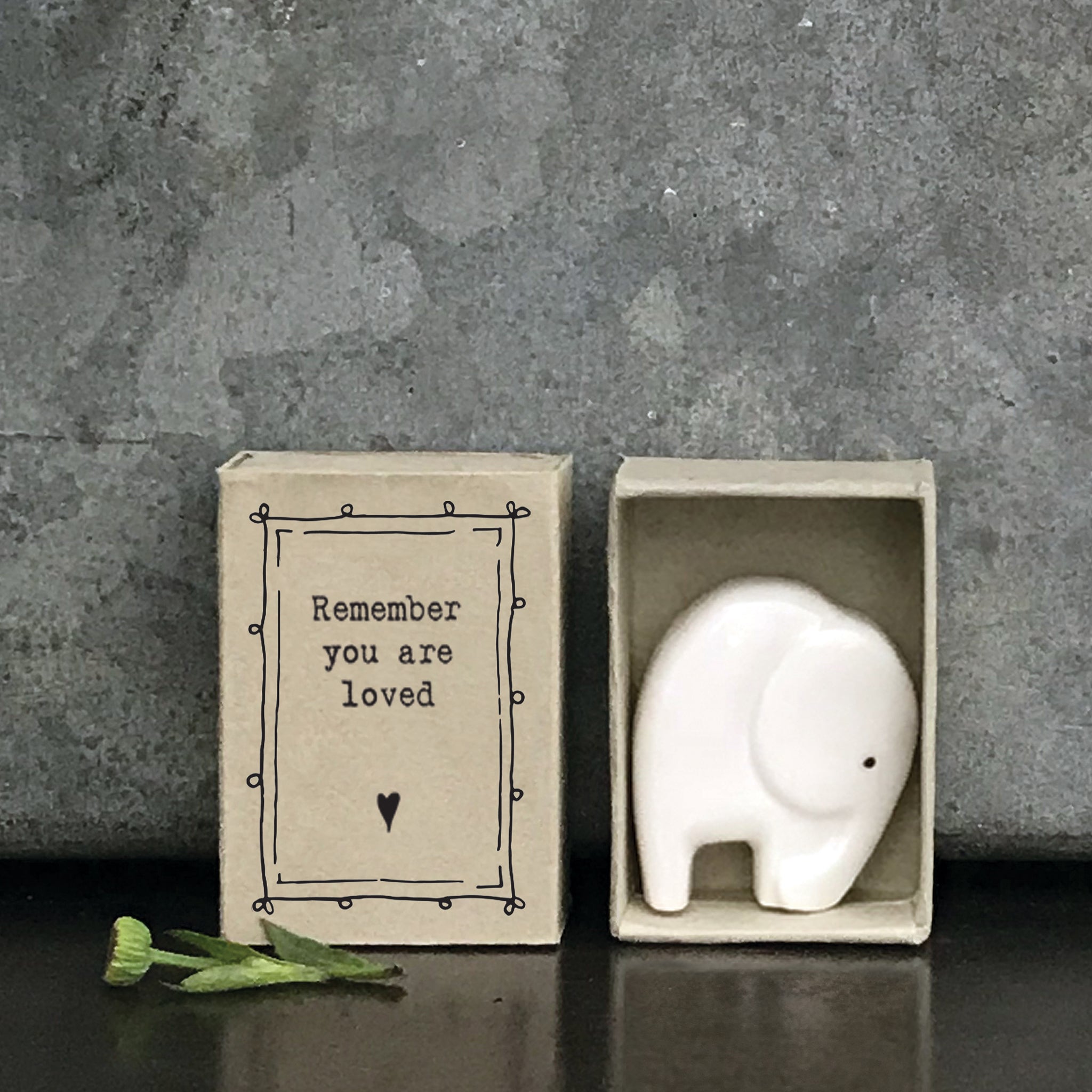 Minimalist white ceramic elephant figurine in a box with a quote