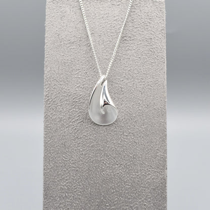 A curved pendant with a twist in a matt and polished silver finish on a silver chain
