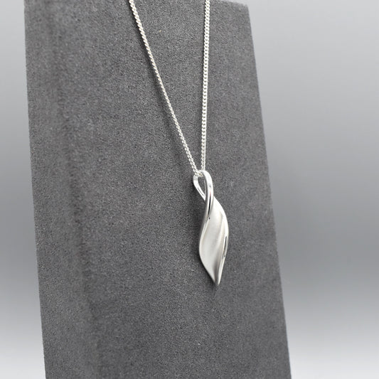 A matt and shiny silver marquis twist shape pendant on silver chain