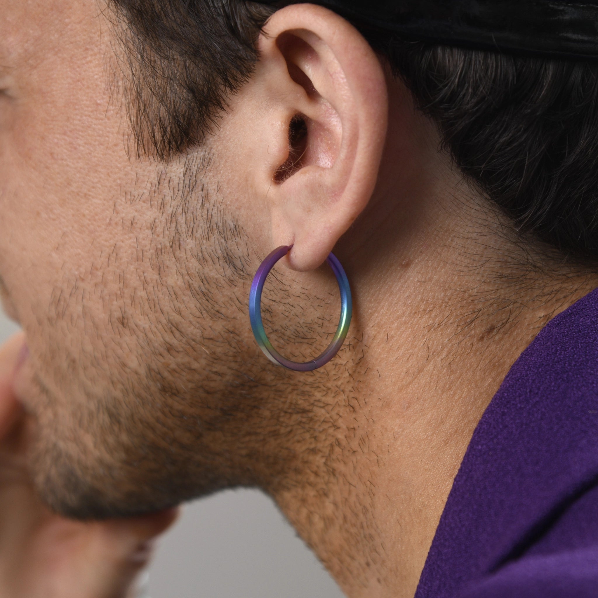 Model wearing a pair of flat hoop earrings in a rainbow ombre colour