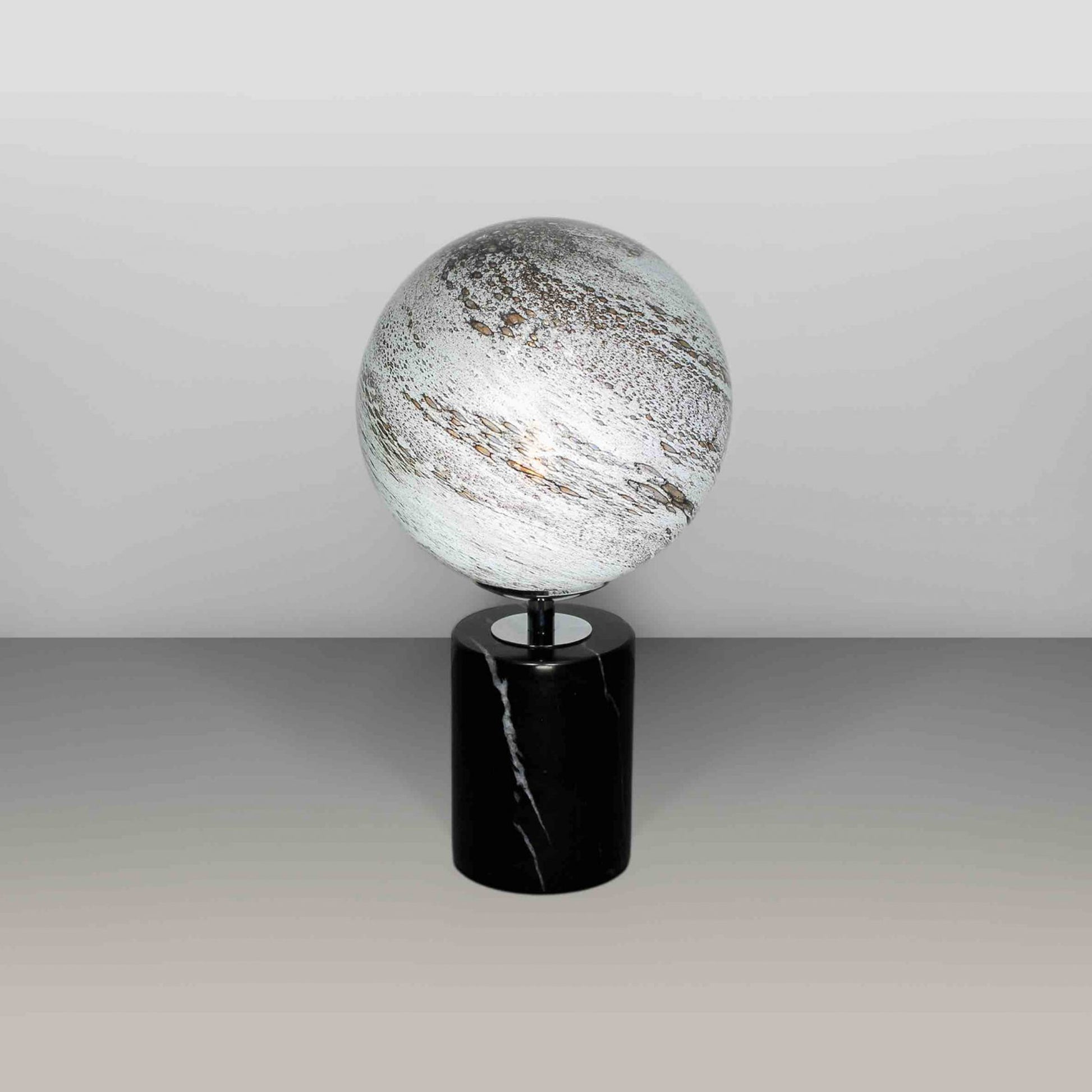 Round glass globe light based on the planet Mercury and set on a black marble base