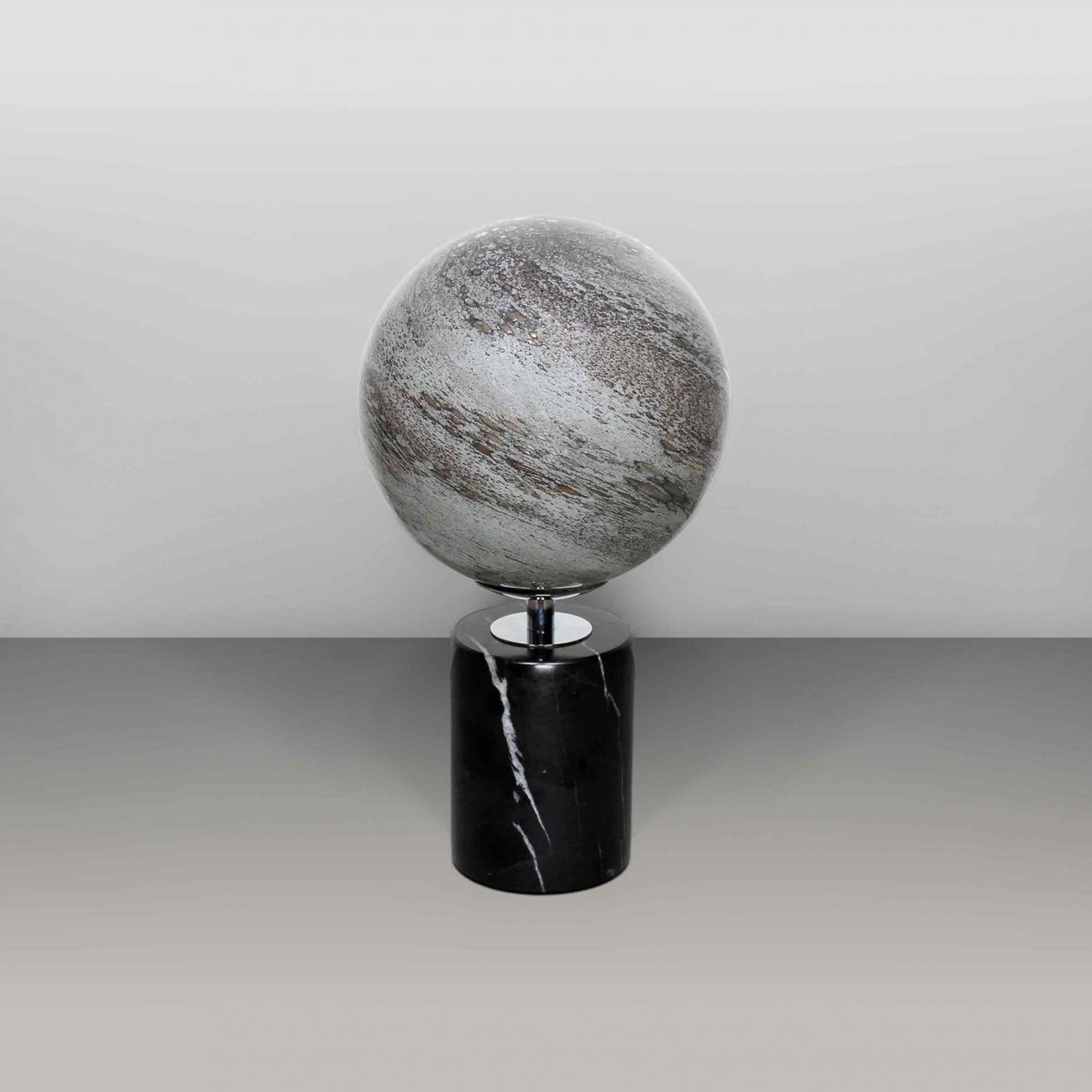 Round glass globe light based on the planet Mercury and set on a black marble base off