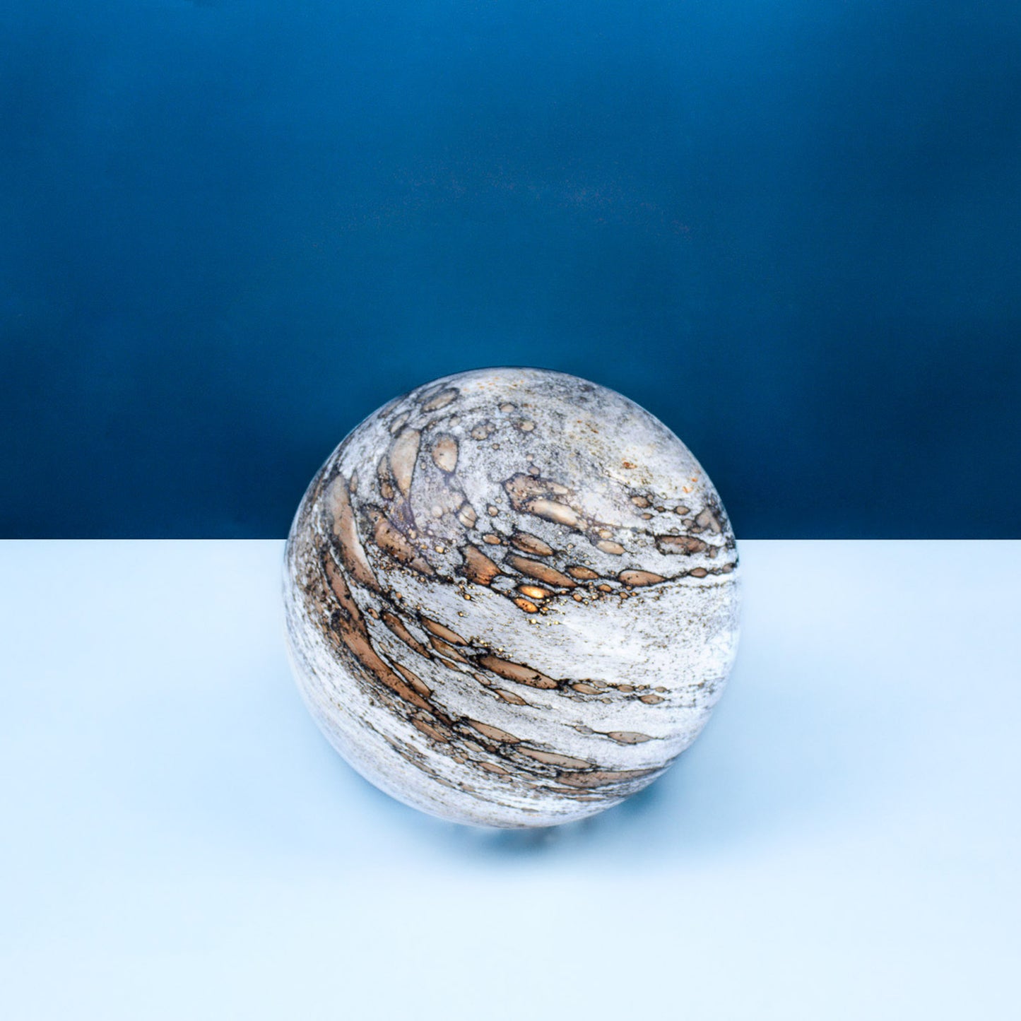 Round glass table light with a design based on the planet mercury and a cool light