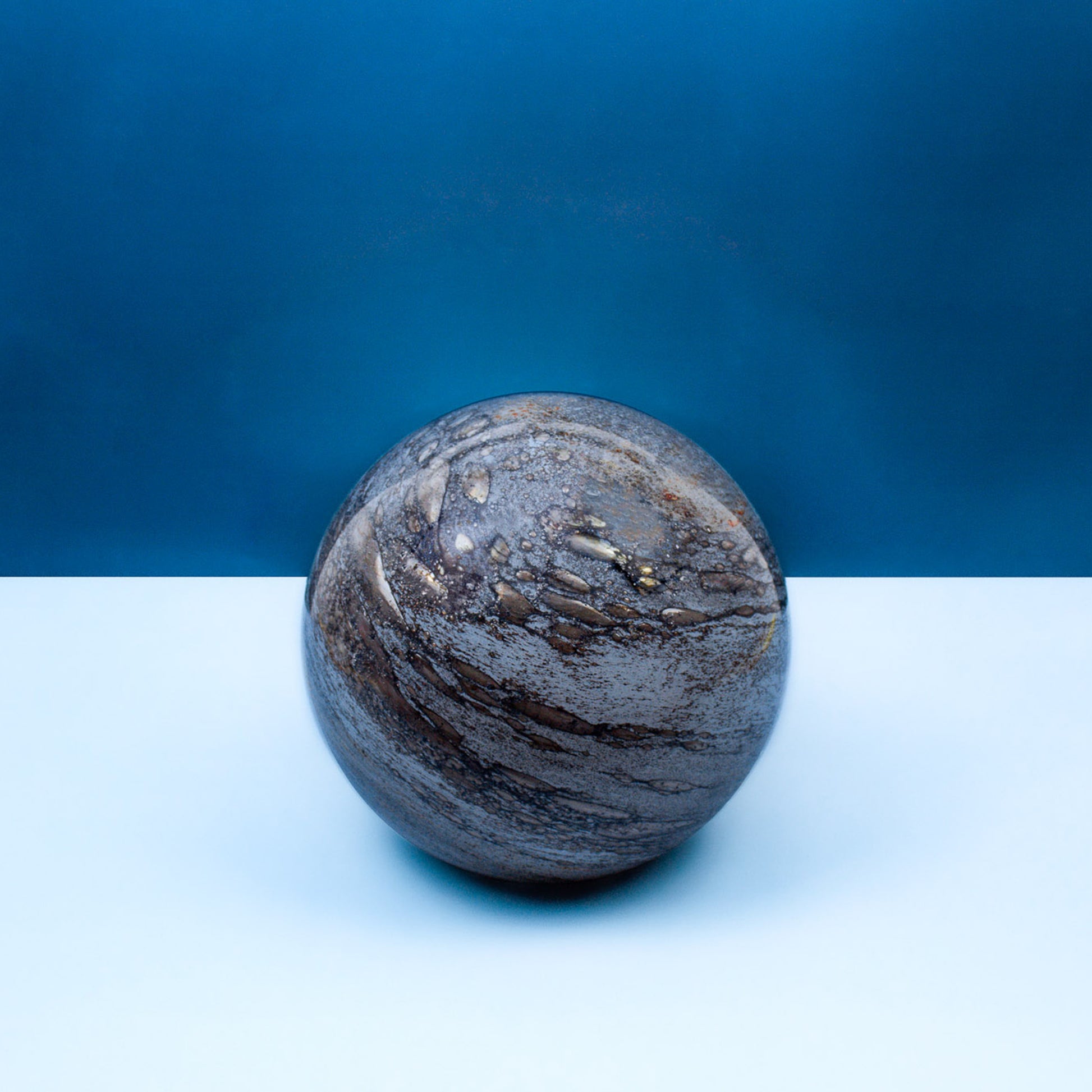 Round glass table light with a design based on the planet mercury off