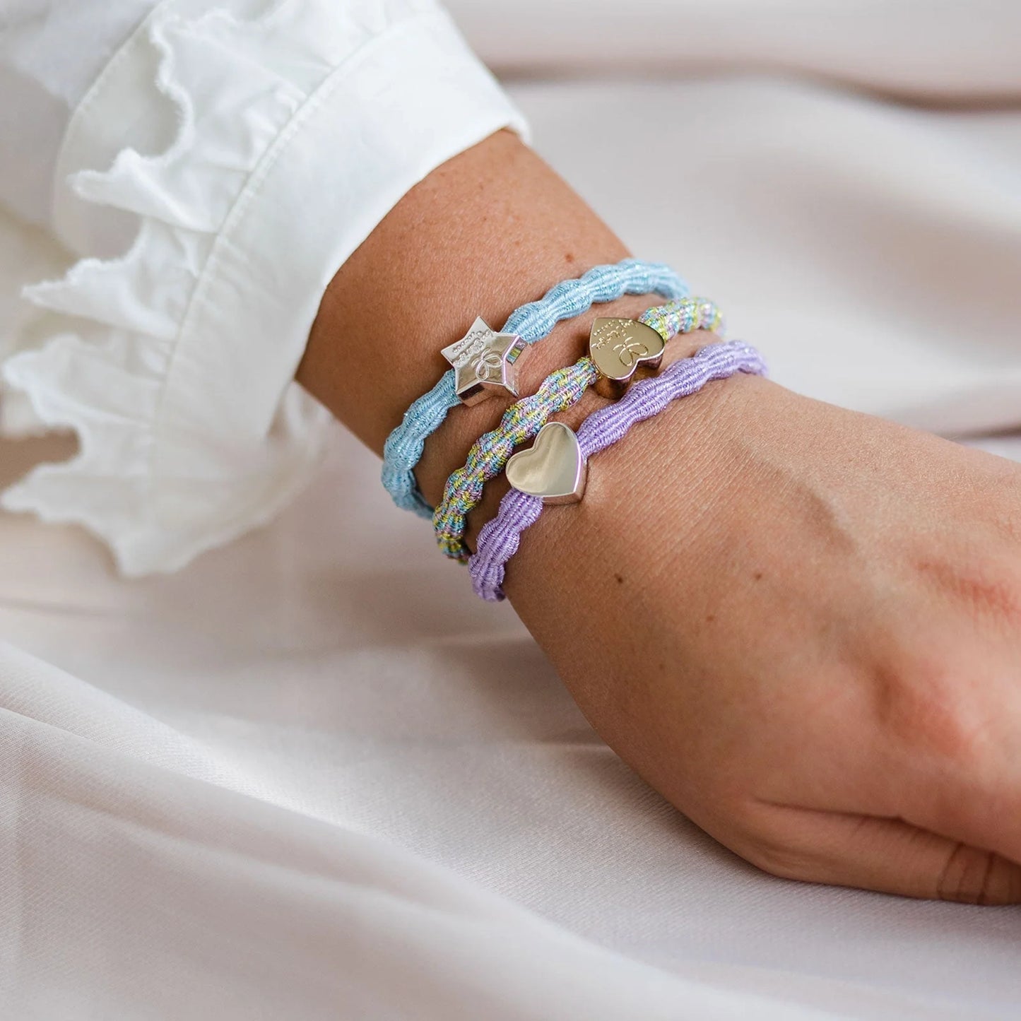 Model wearing metallic bubble shaped hair ties with charms as bangles