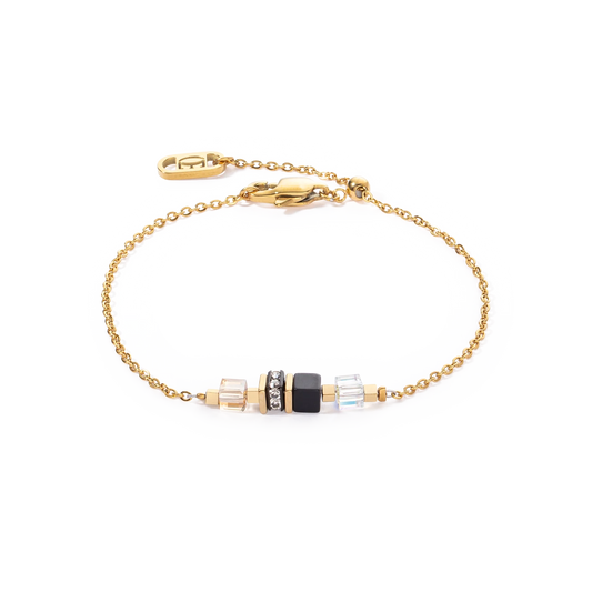 A gold chain bracelet with black cube shaped stones