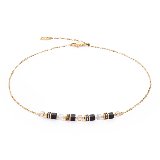 A gold chain necklace with black cube shaped stones