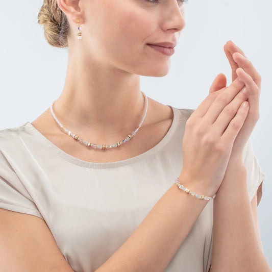 Model wearing a set of jewellery with white and gold mini cube shaped stones and cut glass beads