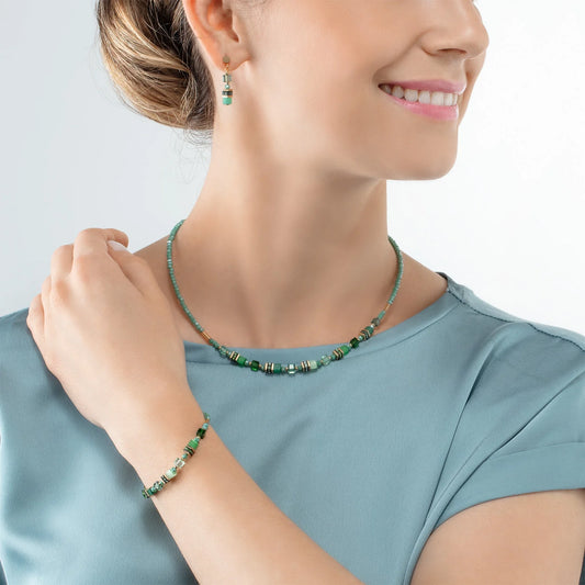 Model wearing a gold necklace with bright green beads and stones
