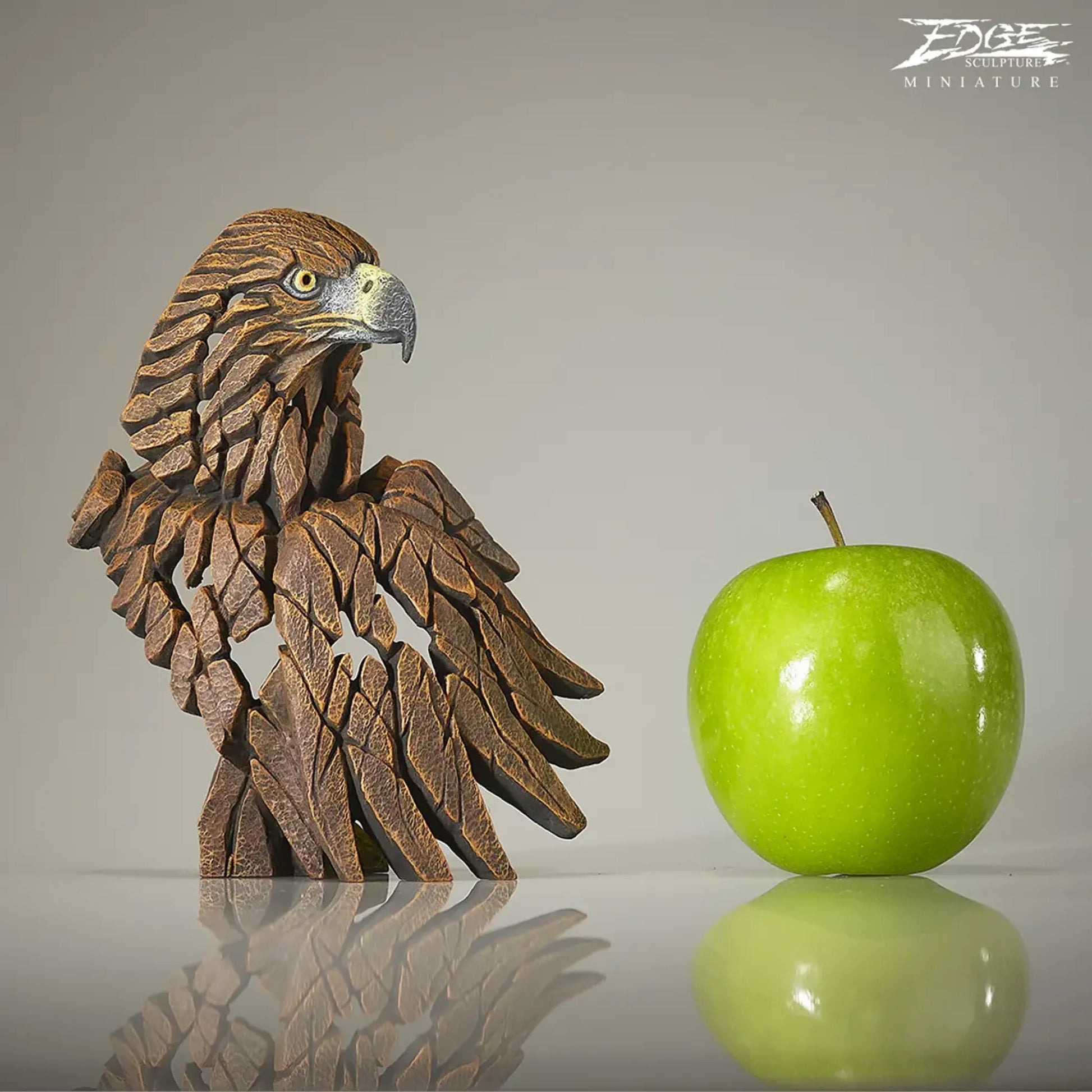 Bust and wing brown painted golden eagle sculpture with size comparison to an apple