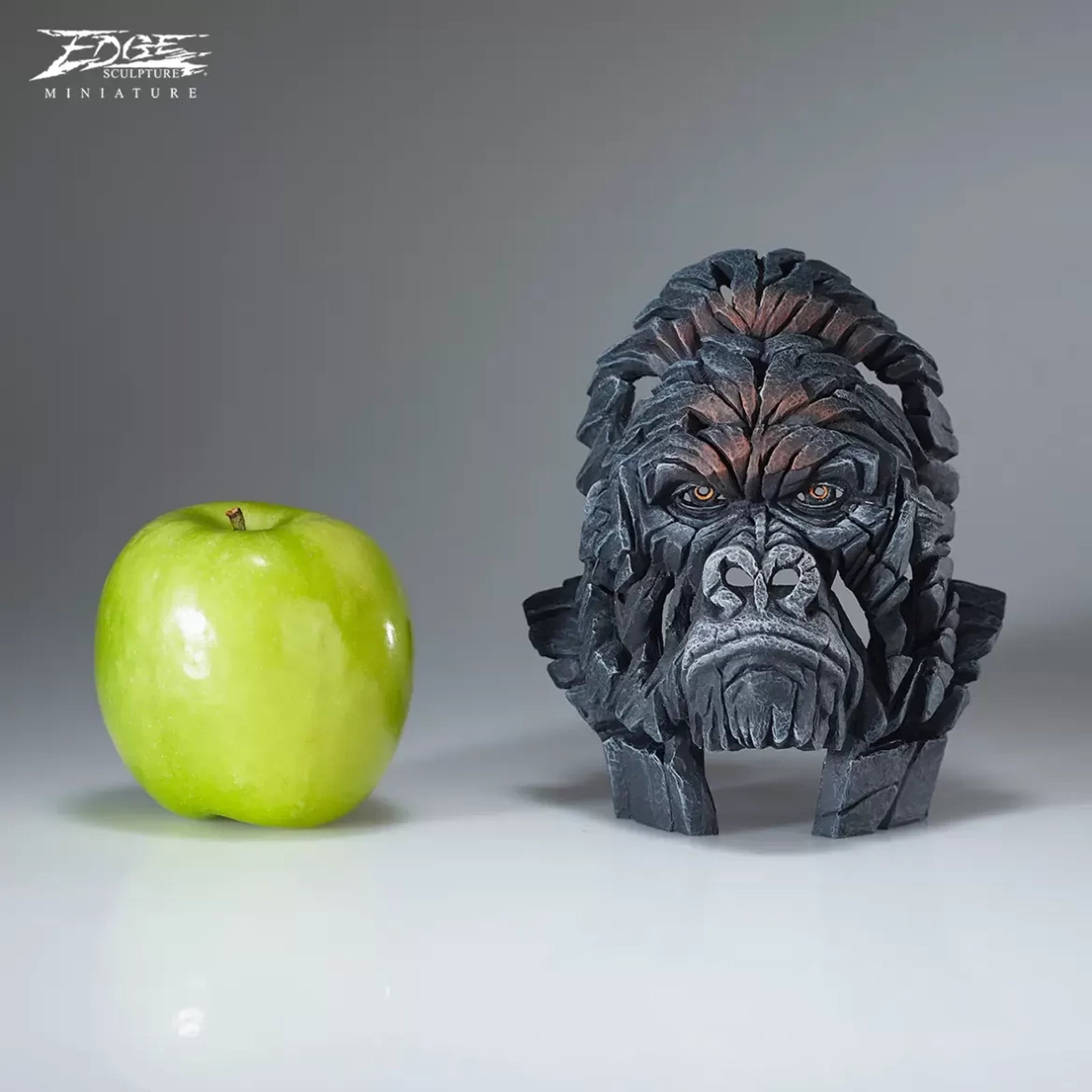 A textured and painted gorilla head bust sculpture size comparison with apple