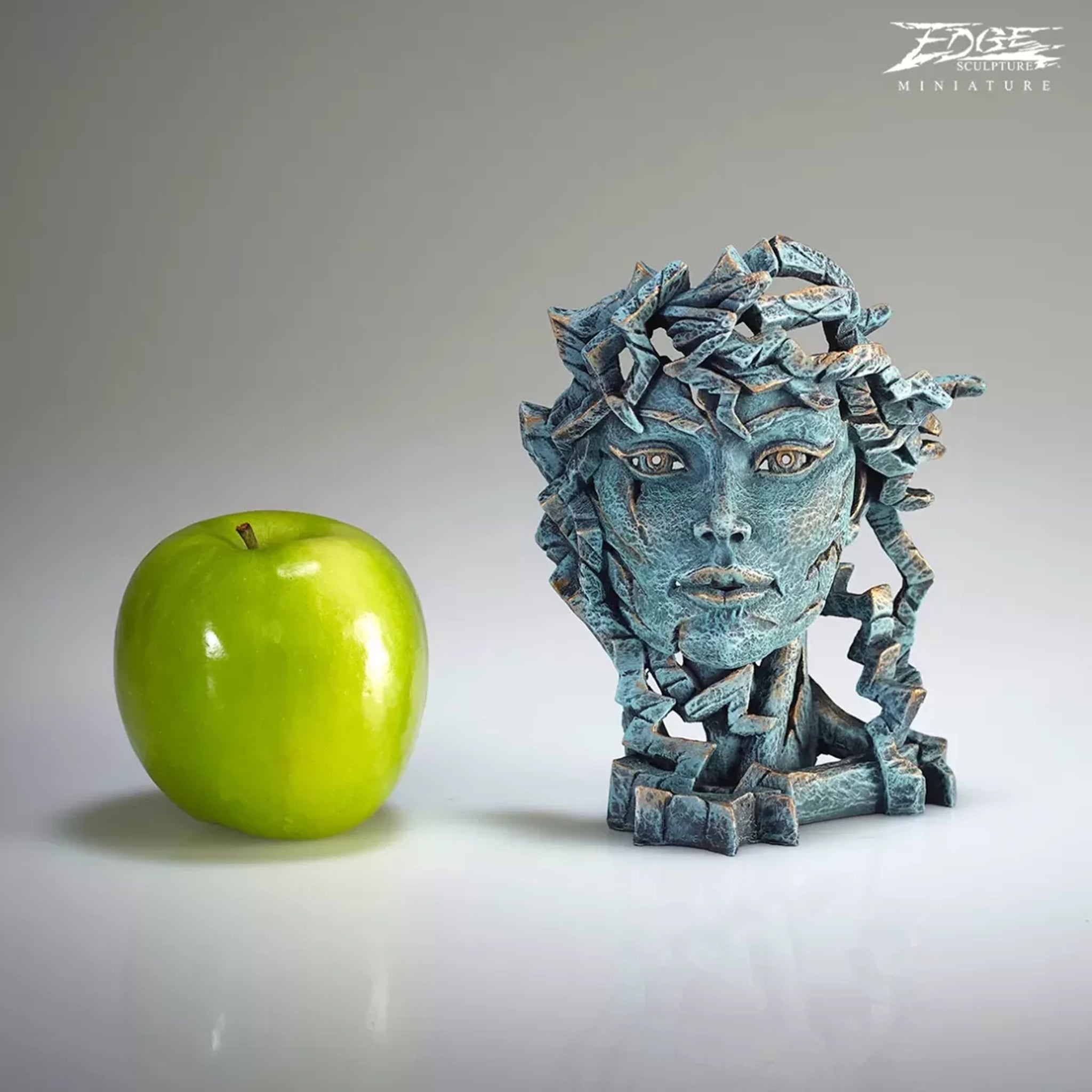 A textured and painted teal Venus head bust sculpture size comparison with apple