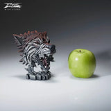 A textured and painted wolf head bust sculpture size comparison with apple