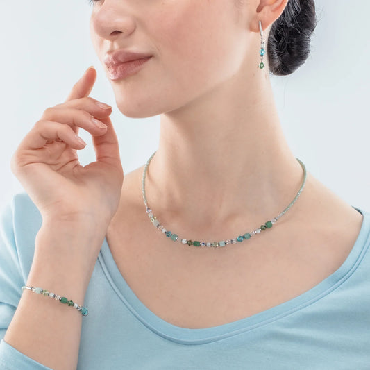 Model wearing a set of jewellery featuring white, green and blue cut glass beads and cube shaped stones