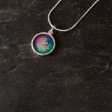 A round pendant with blue and purple enamelling and a silver moon and frame