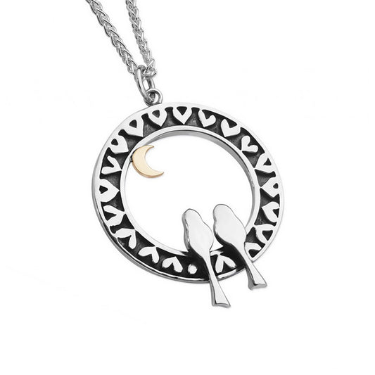 Silver pendant with two birds in a round heart decorated frame with a gold moon at the top, on a silver chain