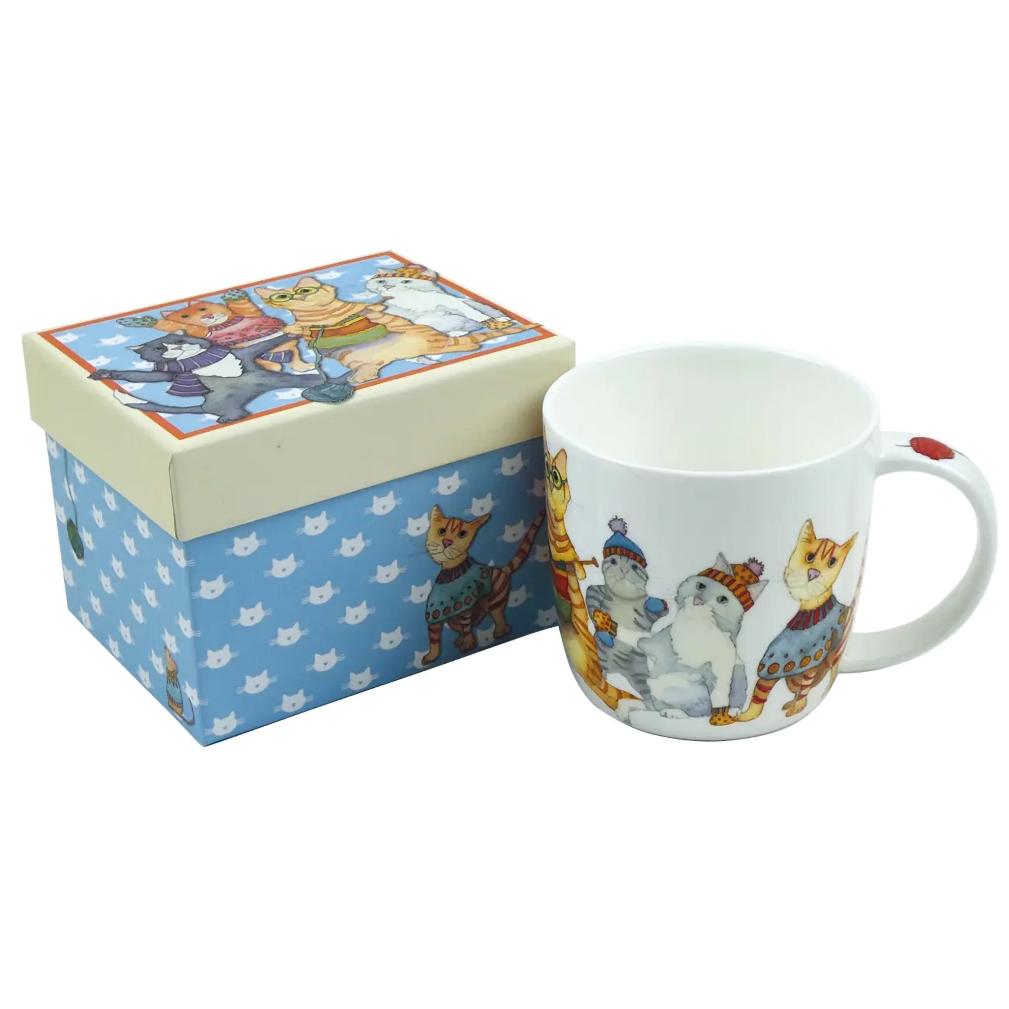A white mug with an illustration of cats in winter clothing next to a matching gift box