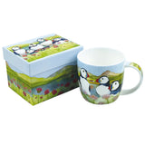 A mug fully illustrated with a watercolour artwork of puffins by the water