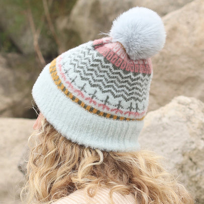 Model wearing multi patterned brushed knitted hat with faux fur pompom in aqua, pink and yellow back view