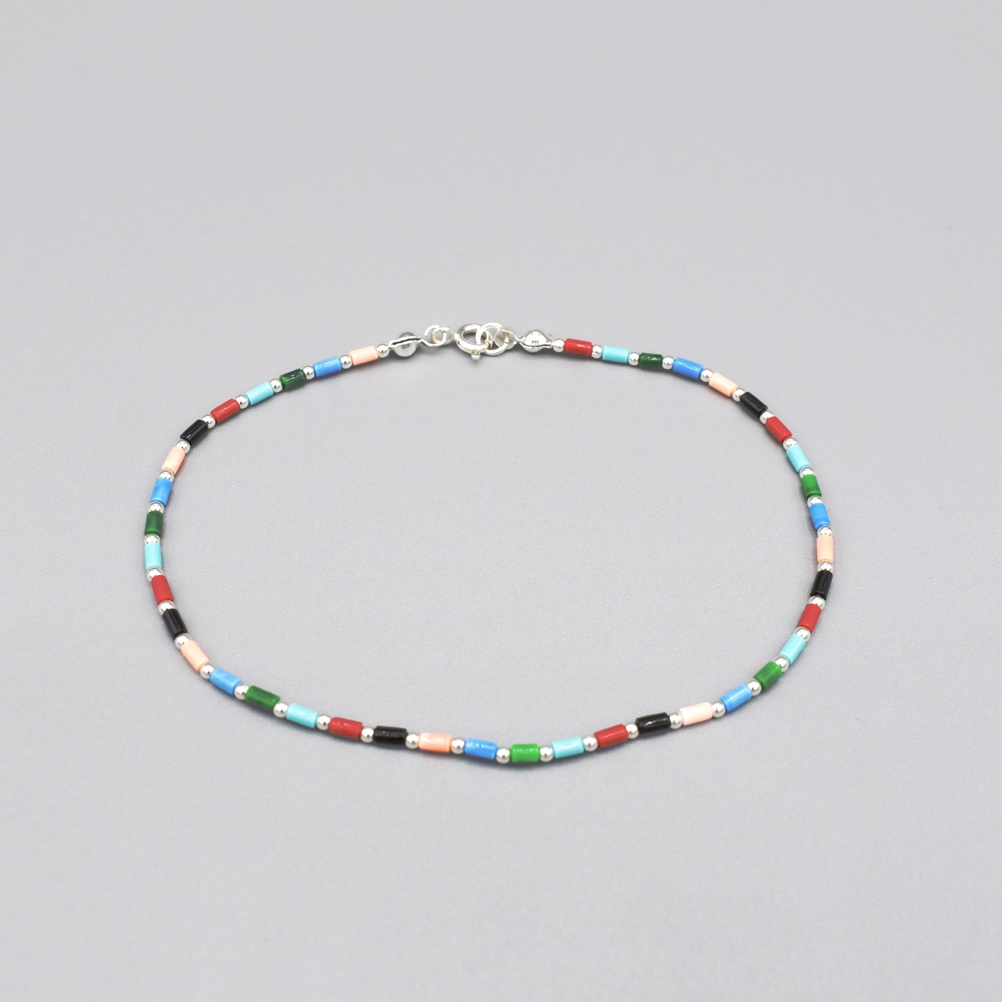 A beaded anklet with cylindrical multicoloured semi precious stones and silver ball spacers