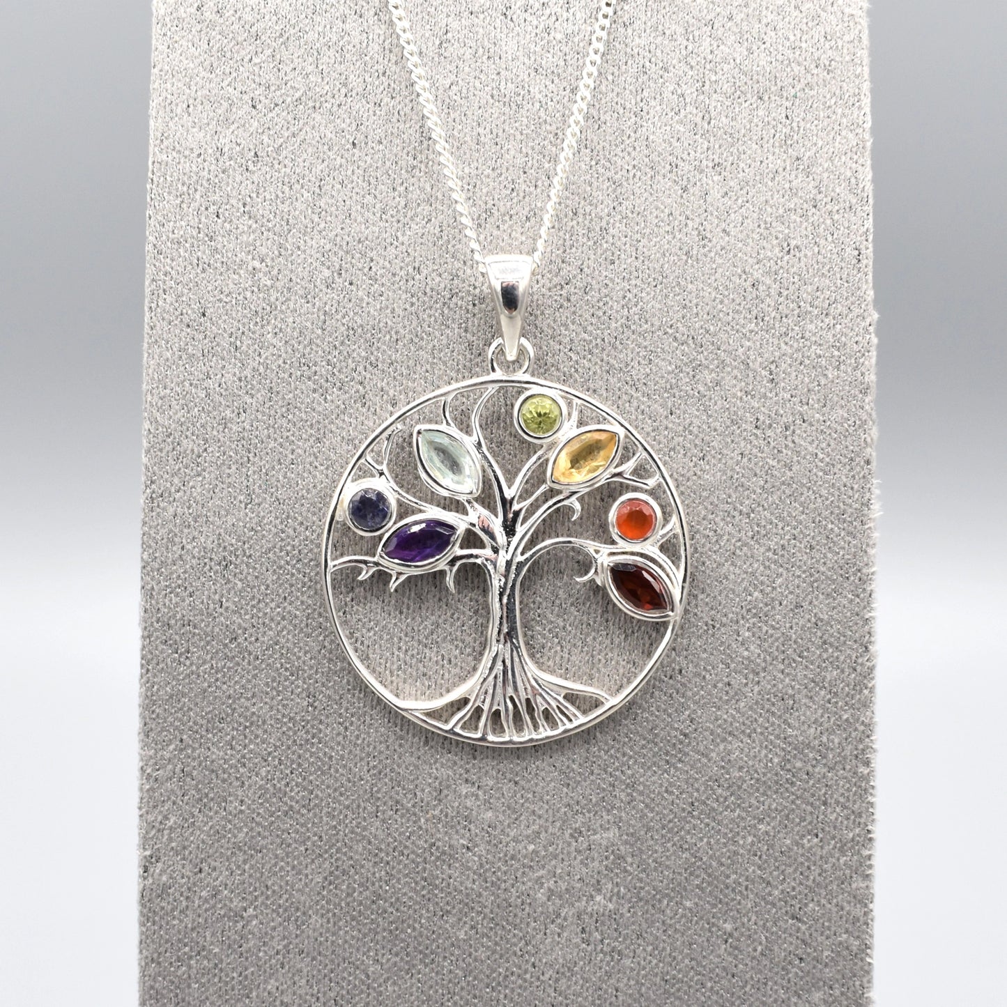 A round silver tree of life pendant with multicoloured gemstones for leaves