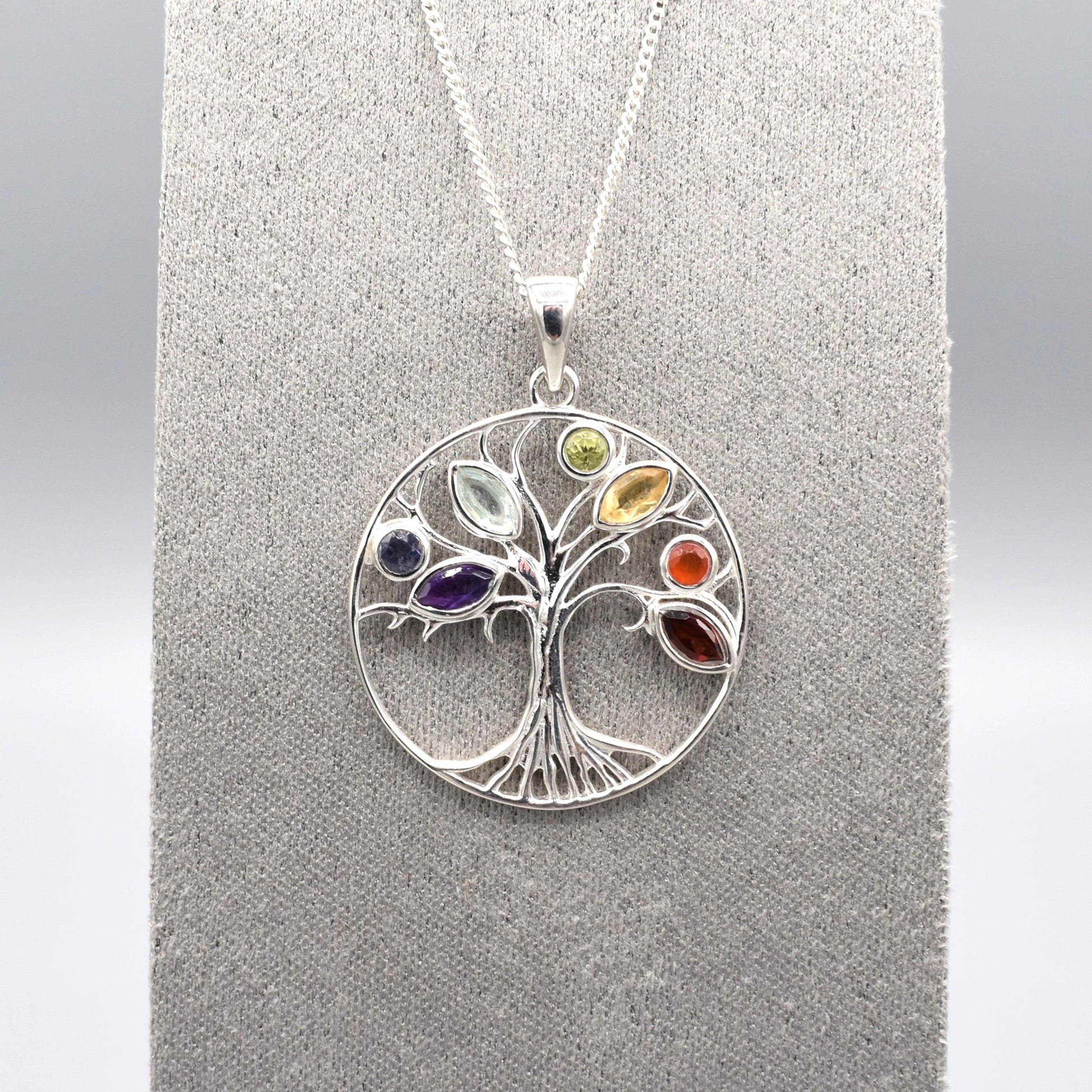 A round silver tree of life pendant with multicoloured gemstones for leaves