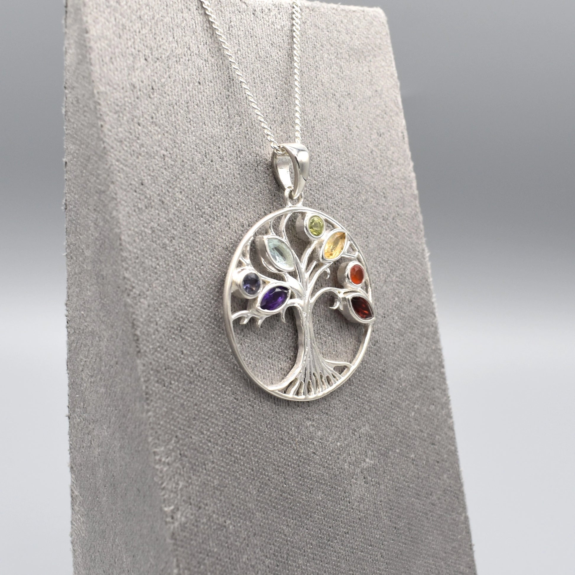 A round silver tree of life pendant with multicoloured gemstones for leaves side