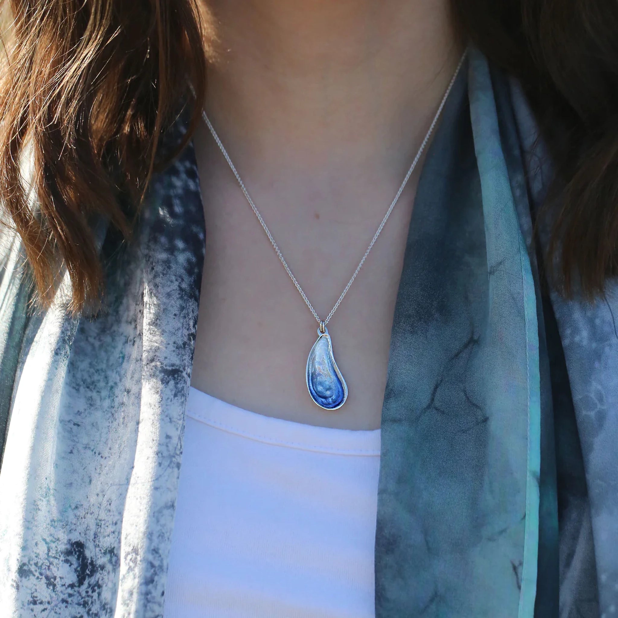 A model wearing a mussel shaped silver pendant with blue enamel
