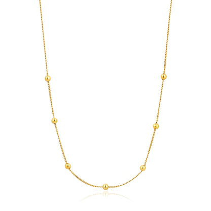 A gold chain necklae featuring 7 gold ball details spaced symmetrically