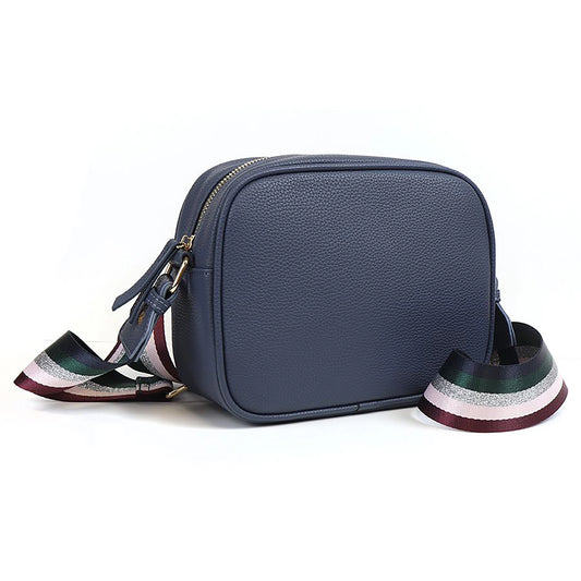 Side view of navy vegan leather cross body camera bag with silver glitter and jewel tone striped print woven strap