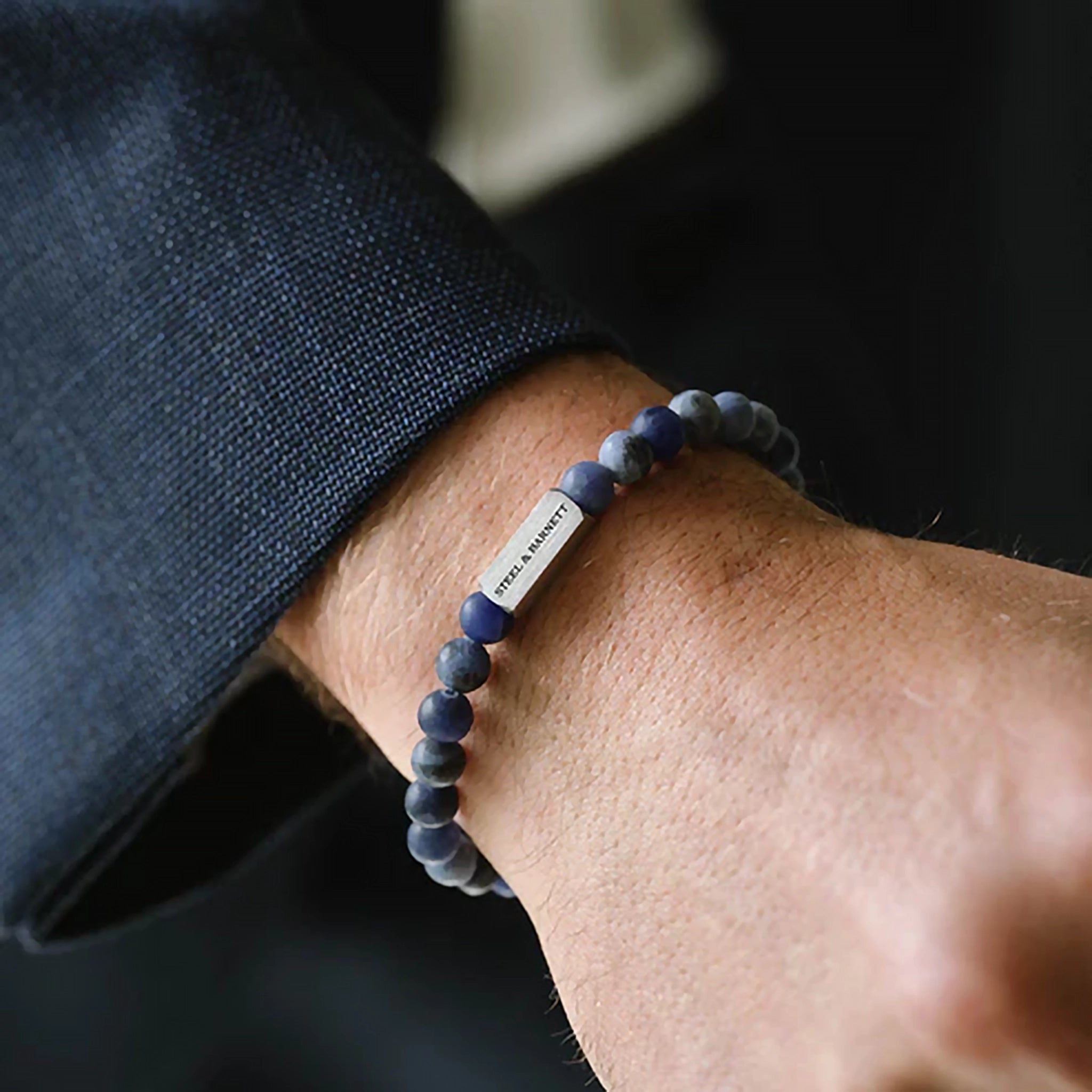 Model wearing a natural sodalite stone elastic bracelet with brushed silver branded stainless steel detail