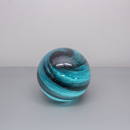 A round glass orb lamp designed based on the planet Neptune in swirls of lights and dark blue