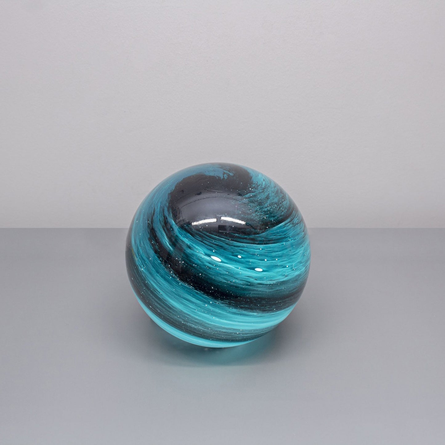 A glass orb light with swirling black and blue colours based on the planet neptune