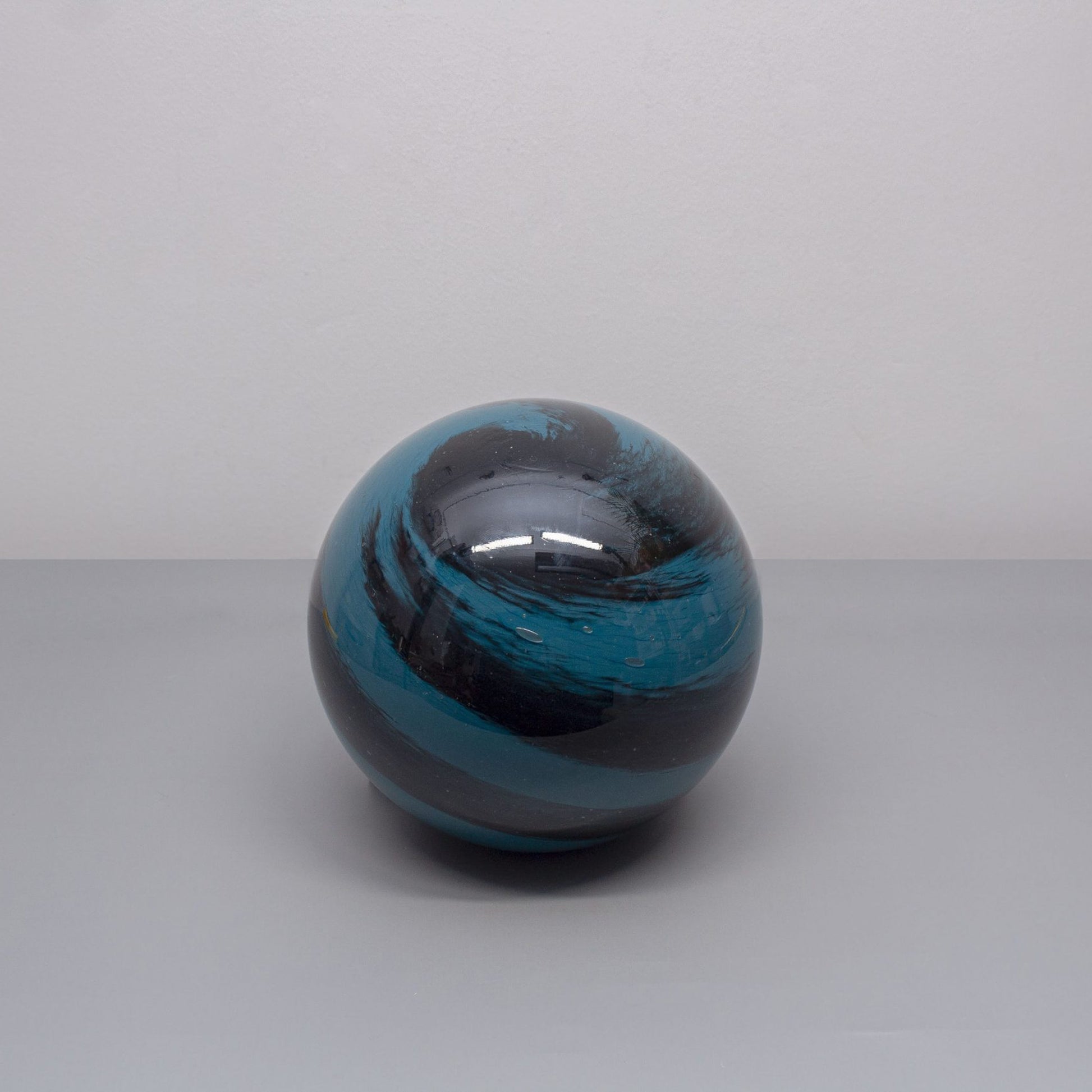 A glass orb light with swirling black and blue colours based on the planet neptune off