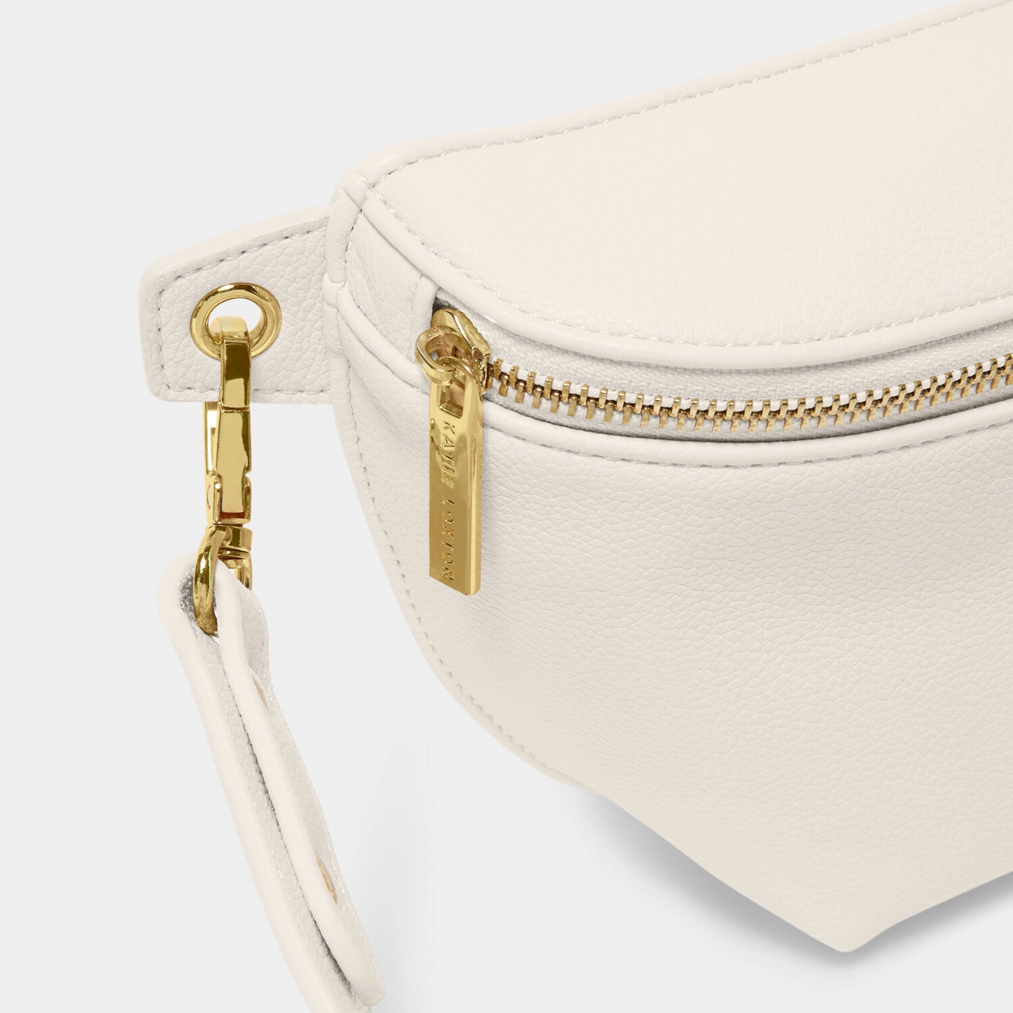 Close-up of gold hardware on off-white faux leather belt bag