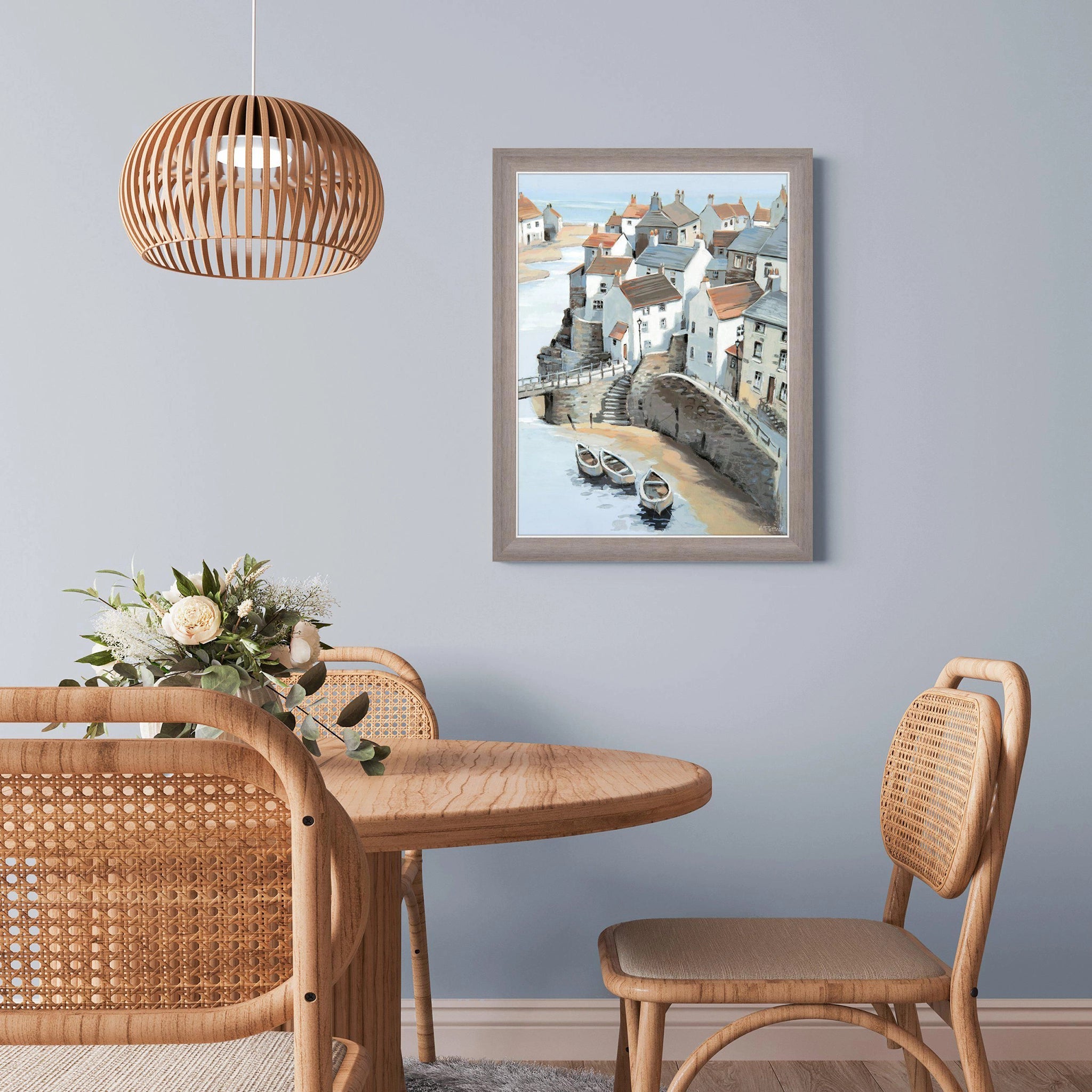 A ashy wood framed wall art print of a painting of a coastal town on wall