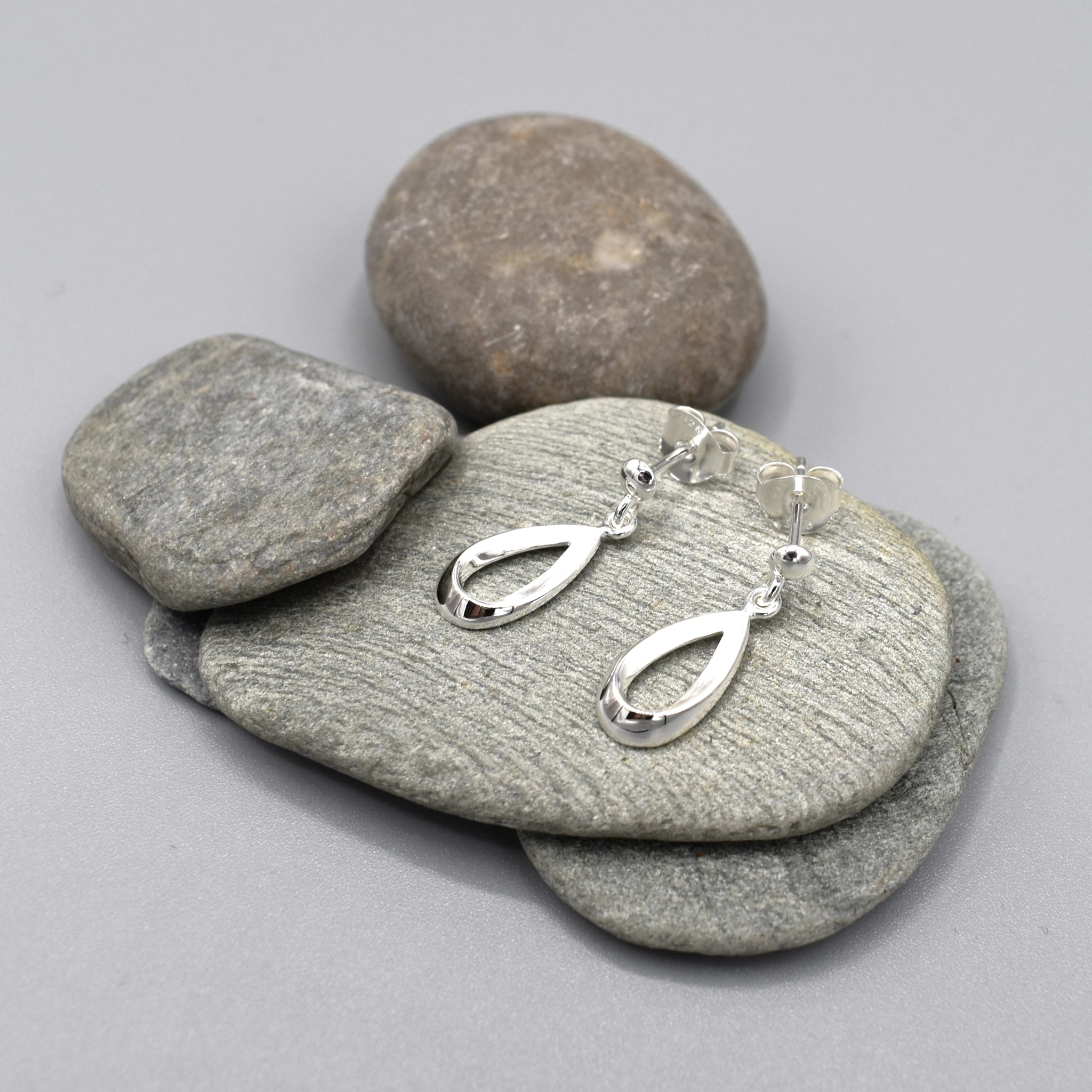 A pair of open bevelled teardrop drop earrings with a silver matt texture