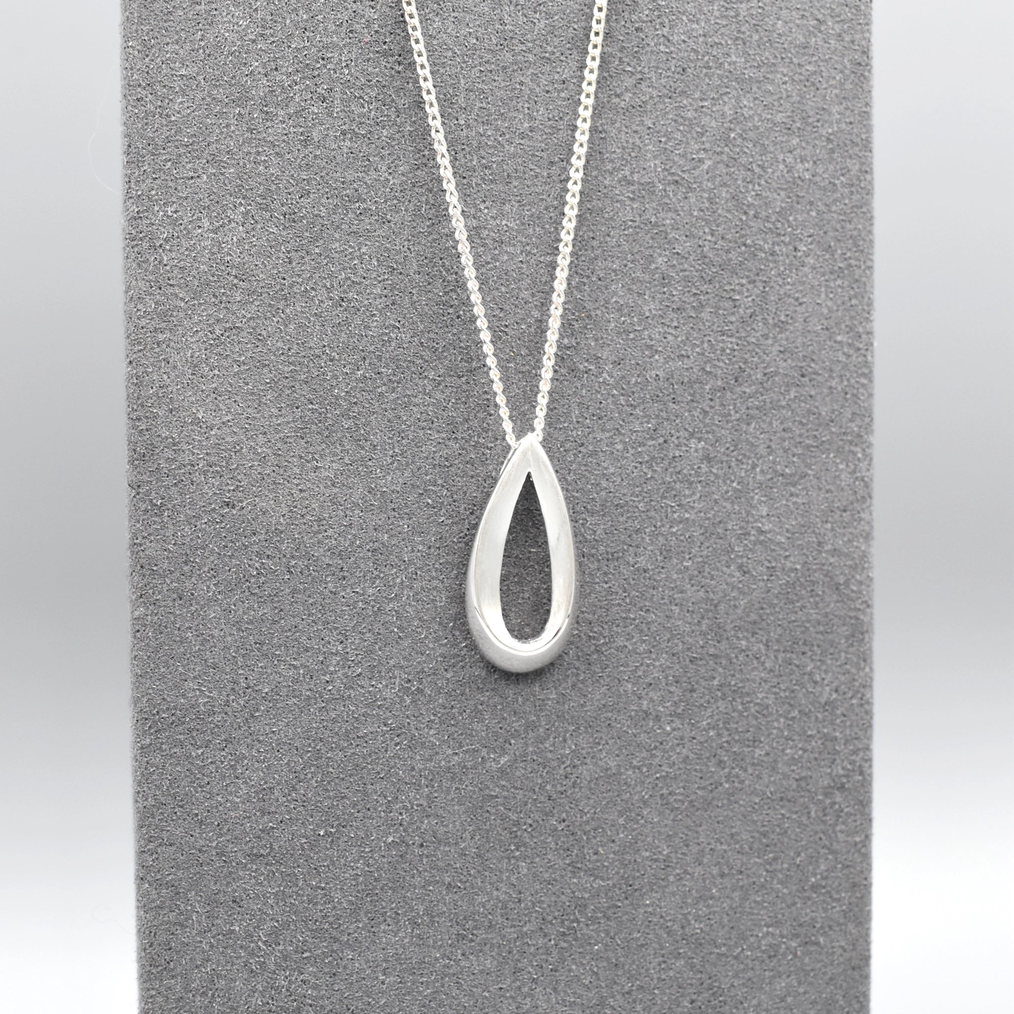 An open bevelled teardrop pendant with a silver matt texture