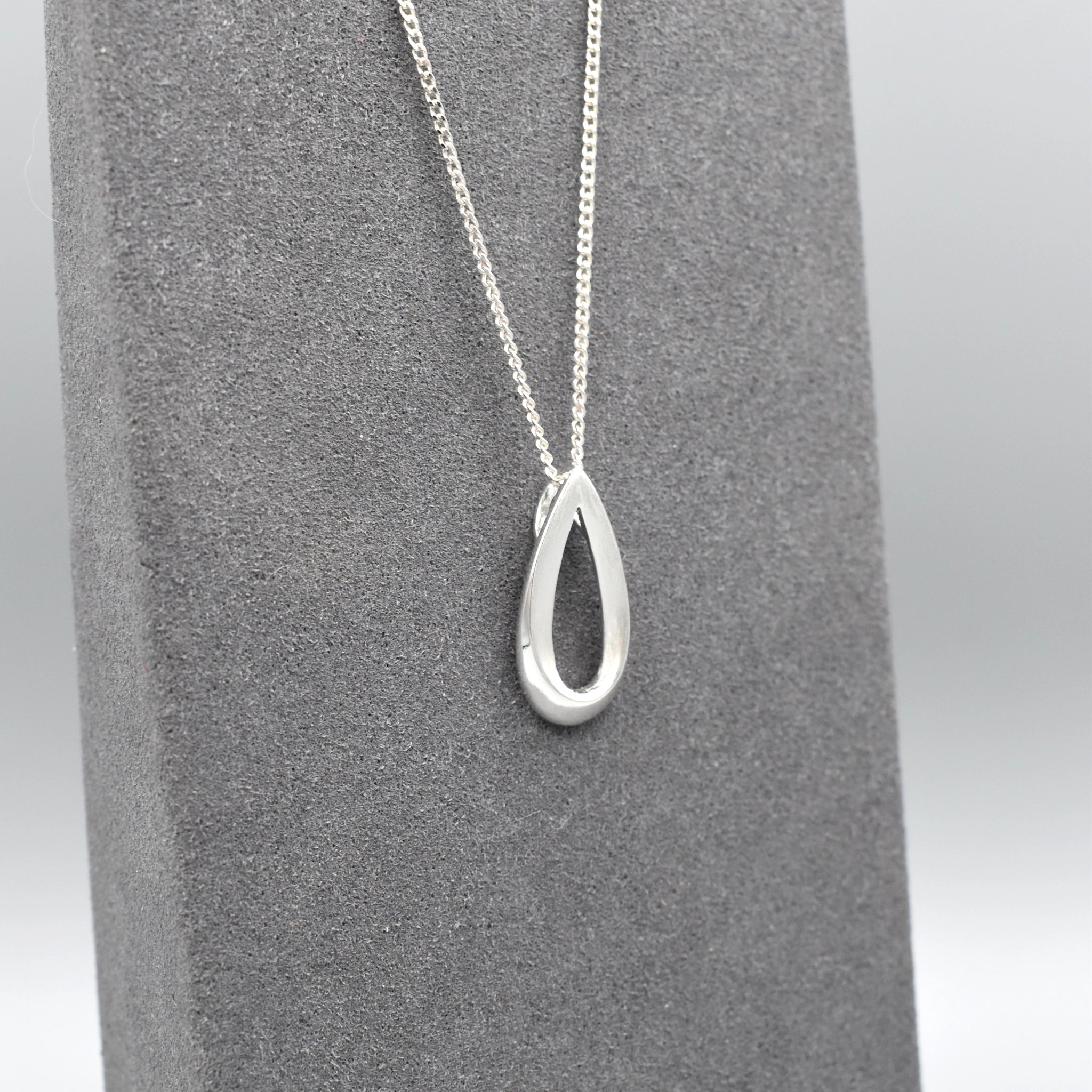 An open bevelled teardrop pendant with a silver matt texture