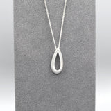 An open bevelled teardrop pendant with a silver matt texture