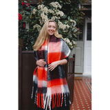 Model wearing a chunky knit black and orange check patterned scarf with tassel trim