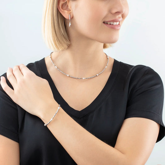 Model wearing a steel necklace with round white pearls and haematite beads