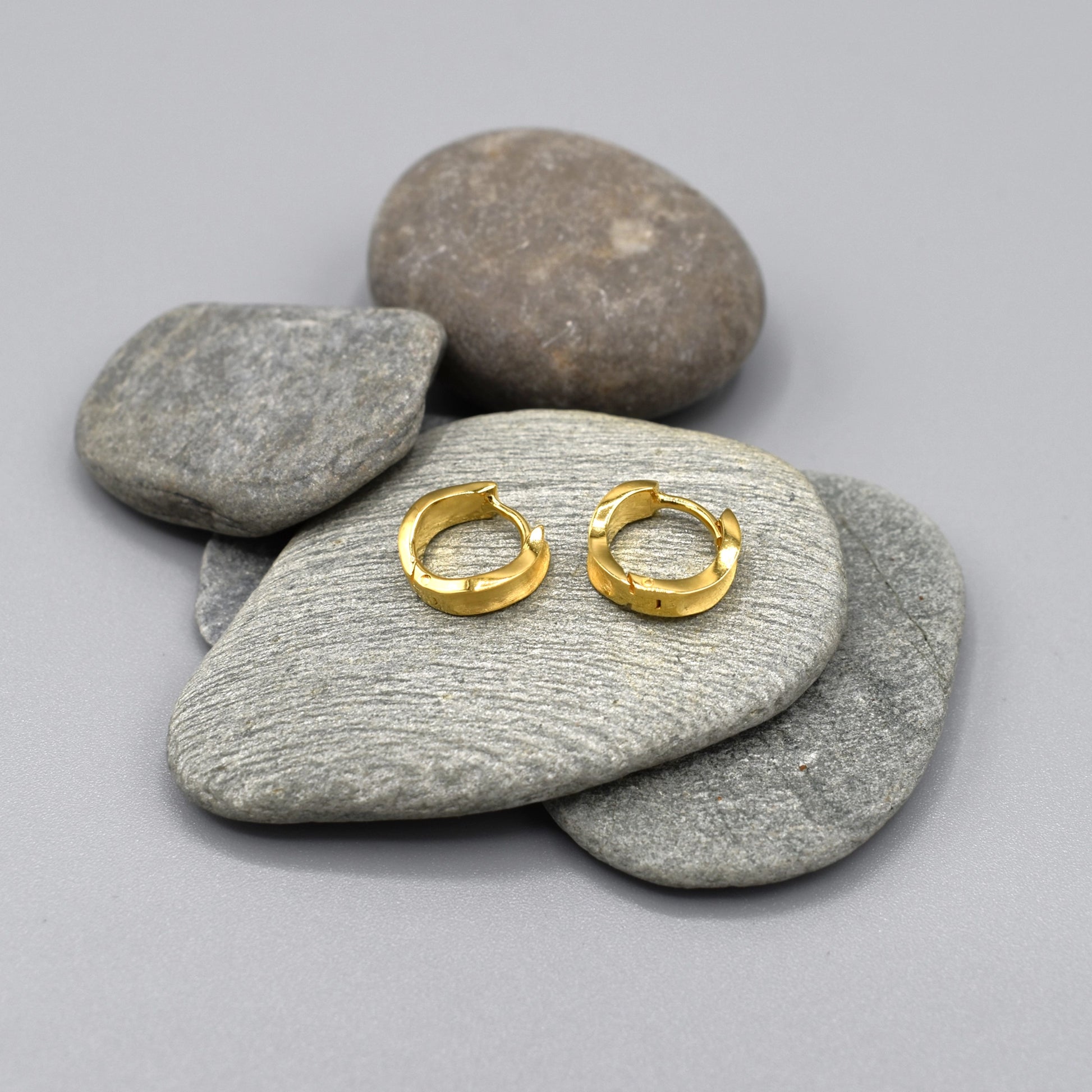 A pair of gold chunky organically shaped huggie hoop earrings