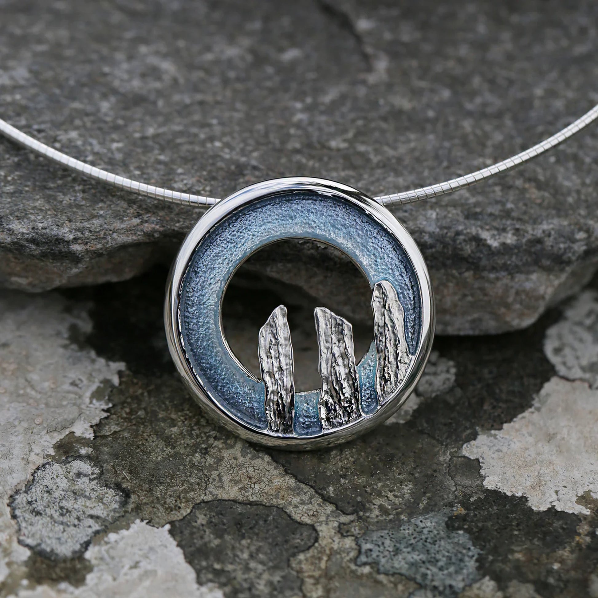 Open circle silver pendant with blue grey enamel and standing stone design on silver wire - lifestyle