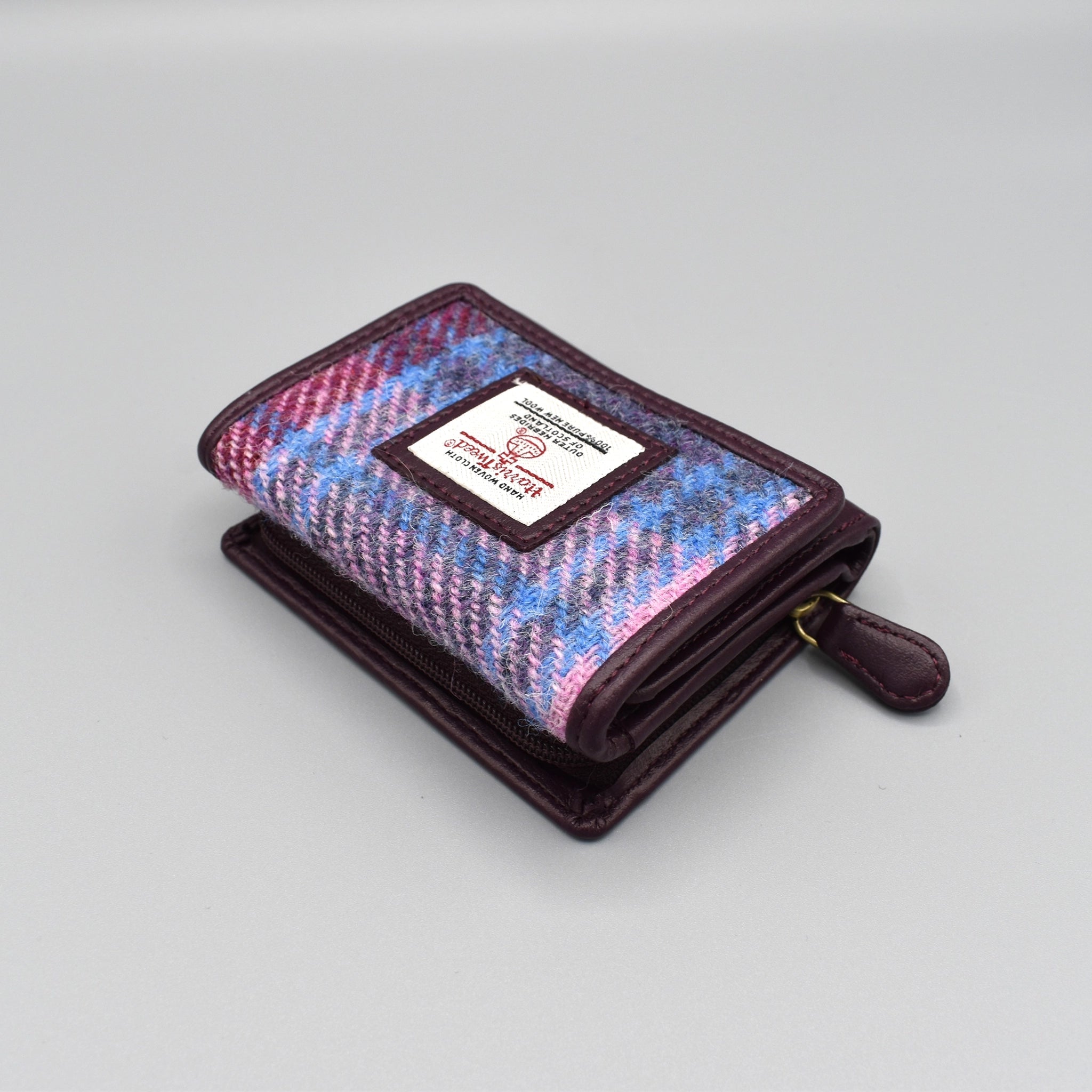 A purple faux leather purse with genuine pastel pink check Harris Tweed in the front with zip